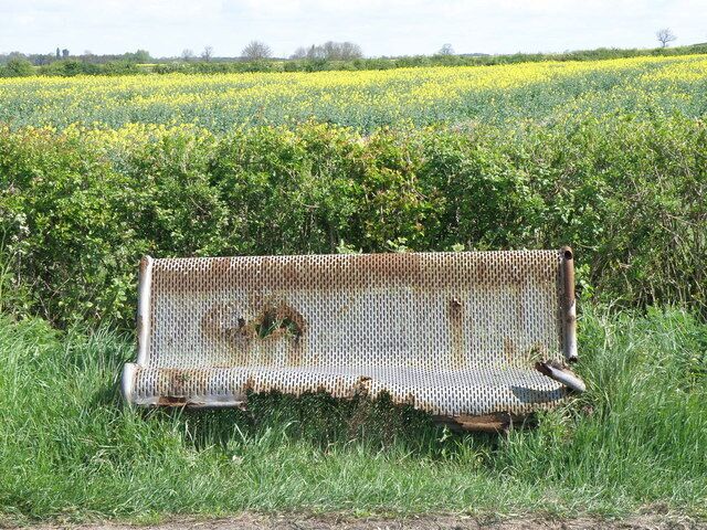 Seen better days The roadside seat on the B663 just out of Raunds looks to be suffering from advanced decay not helped by being so close to the roadside. It probably gets a good dose of salt each winter.