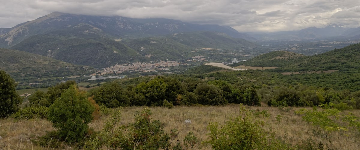 A mountainous landscape with a river, dense forests, and a small town.