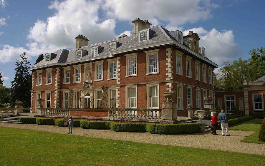A large, historic brick building with multiple chimneys and dormer windows.