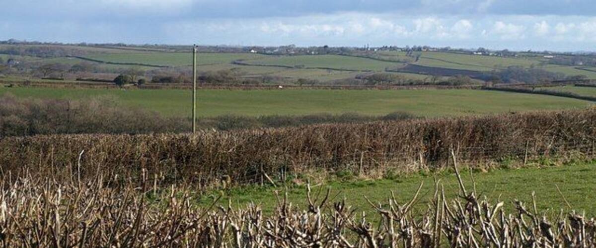 A rural landscape with rolling hills, fields, and a distant village.