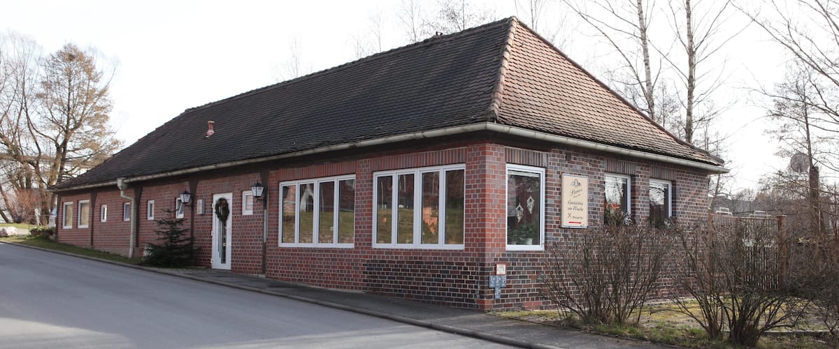 A brick building with a tiled roof, windows, and a sign.