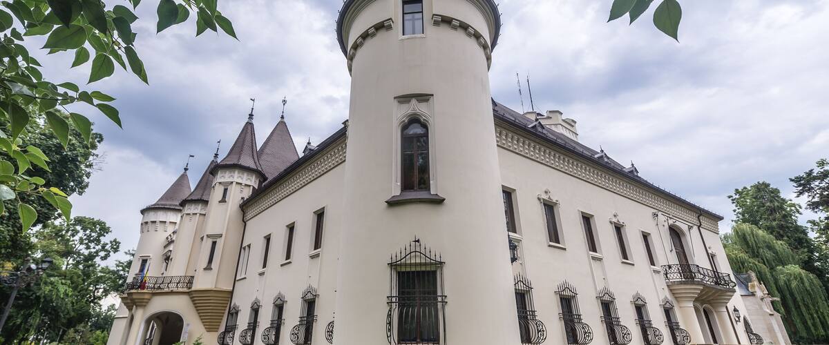 A large, white, castle-like building with multiple towers and a central round tower.