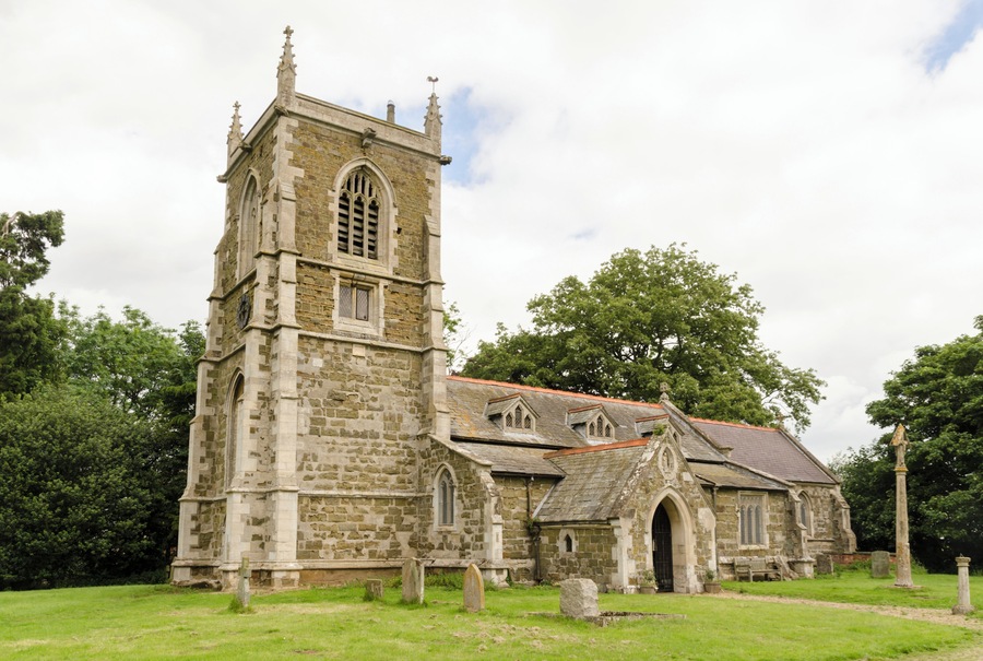 There is no mention of the church in the Domesday book, but there are indications that the first building was early Norman. The church is first documented in 1280. The church is constructed with greenstone with brickwork and ashlar dressings. The roof is slate. There is a western tower, nave with south aisle, chancel, vestry, and south porch. The tower is of three stages dating from the 15th century, it was largely rebuilt in the 19th century. It has a plain parapet and crocketted pinnacles. There is a date stone of 1684 on a plaque which marks the rebuilding of the tower which had collapsed. On the second stage of the tower there is another date stone of 1894 from when the upper part was rebuilt. There a three bay south arcade with octagonal piers from the 15th century. The nave also has three 19th-century dormer windows on the south side which were in inserted in 1911. The chancel was rebuilt in 1870 by James Fowler, the 15th century chancel arch being retained. There is a modern rood loft and screen, the original rood stairs are still present. Either side of the rood are two wooden carved Angels, probably dating from the 15th century and taken from Louth church. In the 19th century porch there is a Norman holy water stoup. There is a 14th century octagonal font set on a Minton tile dias. In 1877 the church underwent major restoration which included new roofs, porch, installation of heating, new floors plus other improvements. This was not finished until 1894 due to financial issues.