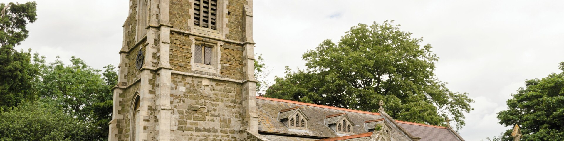 There is no mention of the church in the Domesday book, but there are indications that the first building was early Norman. The church is first documented in 1280. The church is constructed with greenstone with brickwork and ashlar dressings. The roof is slate. There is a western tower, nave with south aisle, chancel, vestry, and south porch. The tower is of three stages dating from the 15th century, it was largely rebuilt in the 19th century. It has a plain parapet and crocketted pinnacles. There is a date stone of 1684 on a plaque which marks the rebuilding of the tower which had collapsed. On the second stage of the tower there is another date stone of 1894 from when the upper part was rebuilt. There a three bay south arcade with octagonal piers from the 15th century. The nave also has three 19th-century dormer windows on the south side which were in inserted in 1911. The chancel was rebuilt in 1870 by James Fowler, the 15th century chancel arch being retained. There is a modern rood loft and screen, the original rood stairs are still present. Either side of the rood are two wooden carved Angels, probably dating from the 15th century and taken from Louth church. In the 19th century porch there is a Norman holy water stoup. There is a 14th century octagonal font set on a Minton tile dias. In 1877 the church underwent major restoration which included new roofs, porch, installation of heating, new floors plus other improvements. This was not finished until 1894 due to financial issues.