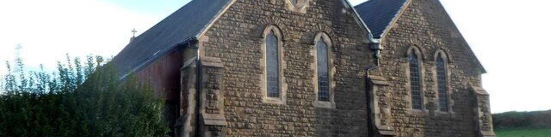 Una iglesia de piedra con un campanario y ventanas de arco.