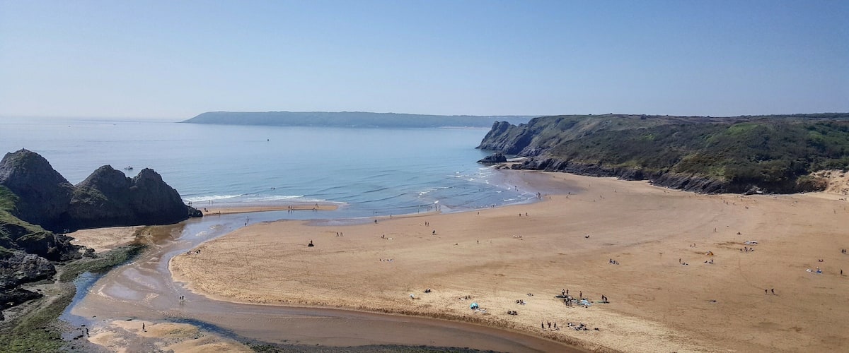 A coastal beach with rocky cliffs and a sandy shore.