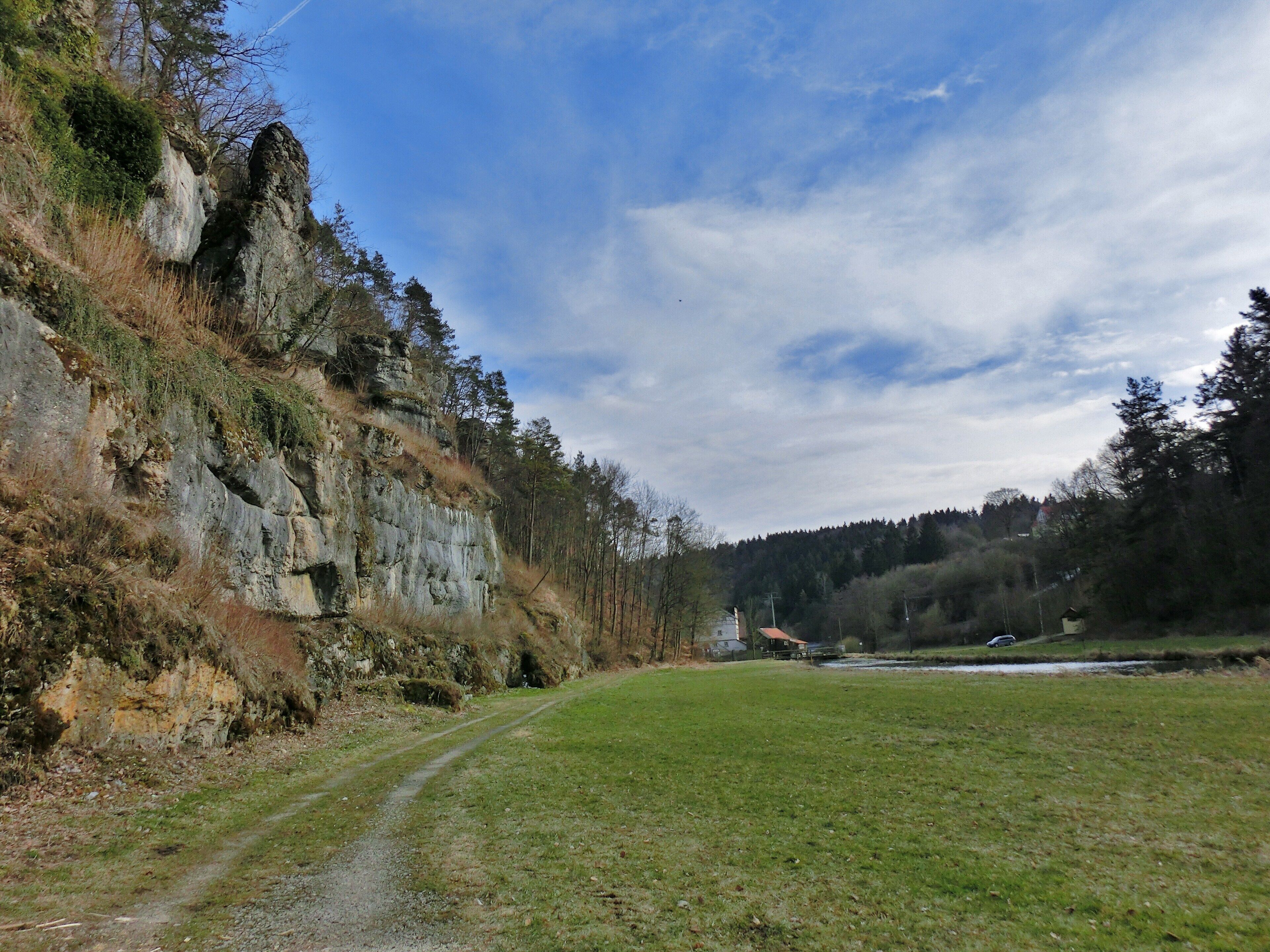 A grassy field with a rocky cliff and a clear sky.