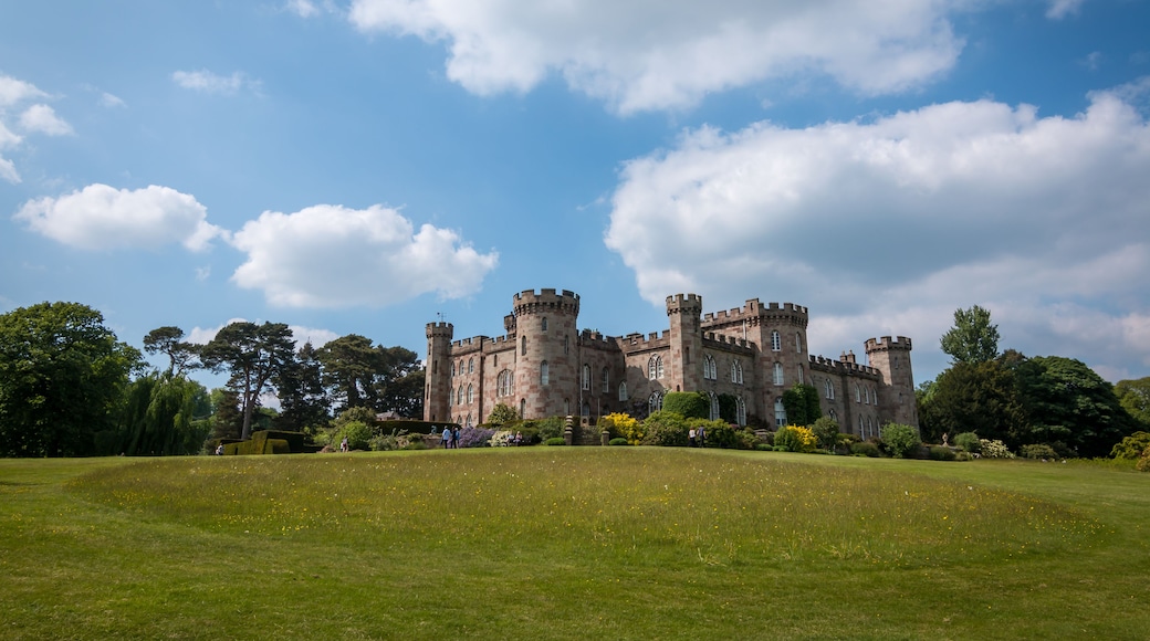 A historic castle with multiple towers and a well-maintained lawn in front.