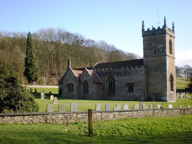 A historic stone church with a tall tower and a graveyard in the foreground.