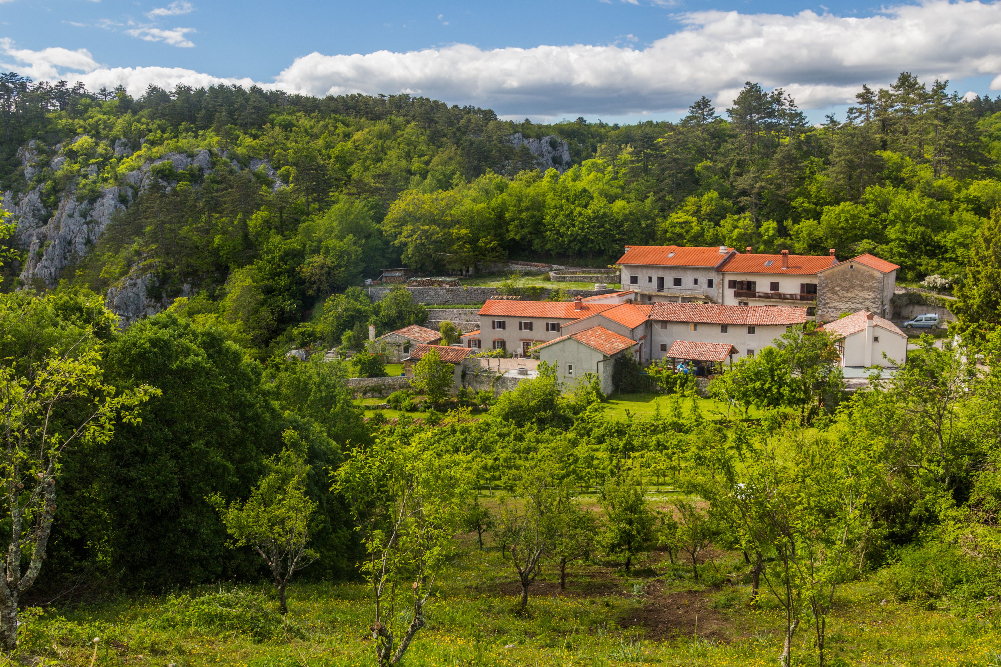Ein Dorf eingebettet in ein Tal, mit terrassenförmig angelegten Häusern und üppiger Vegetation.