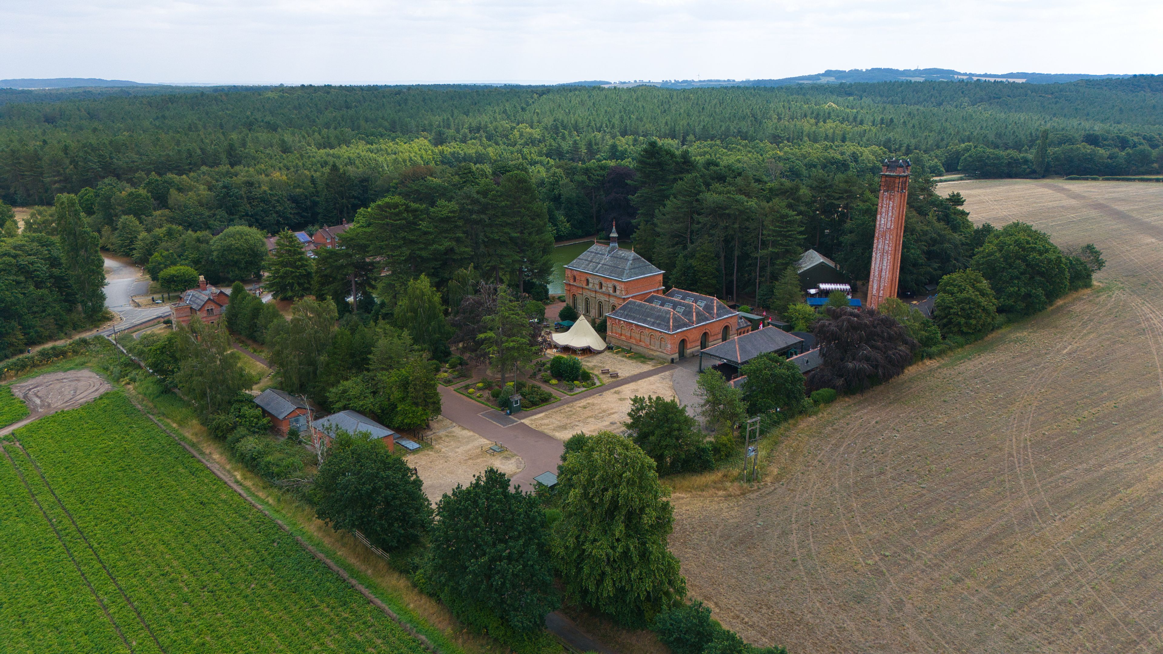 Vista aérea de un paisaje rural con un gran edificio de ladrillo rodeado de árboles y campos.