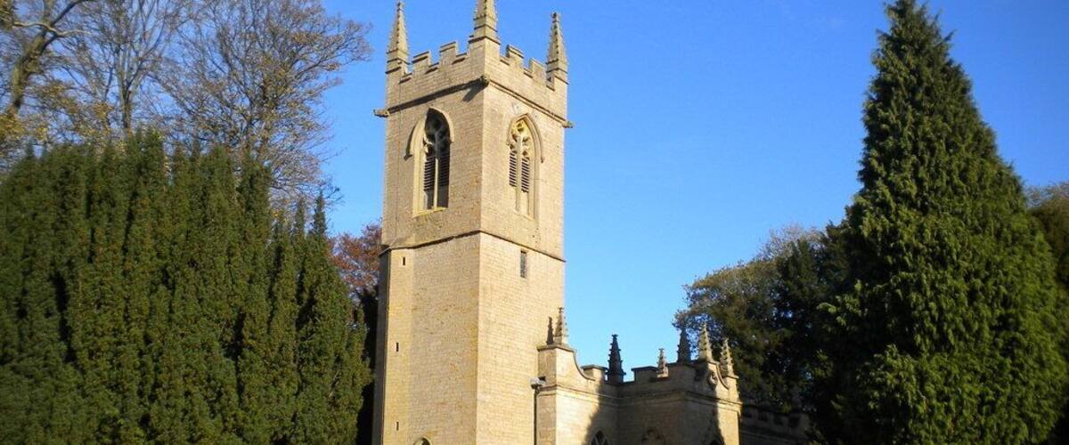 A church with a tall tower and a cemetery in the foreground.