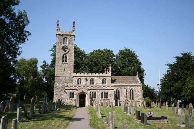 A church with a tall clock tower and a graveyard in front.