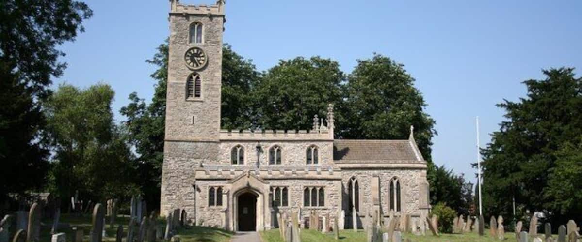 A church with a tall clock tower and a graveyard in front.