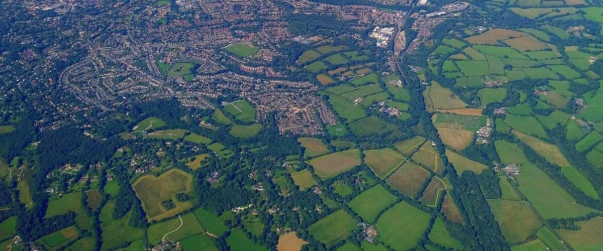 An aerial view of a town surrounded by green fields and patches of farmland.