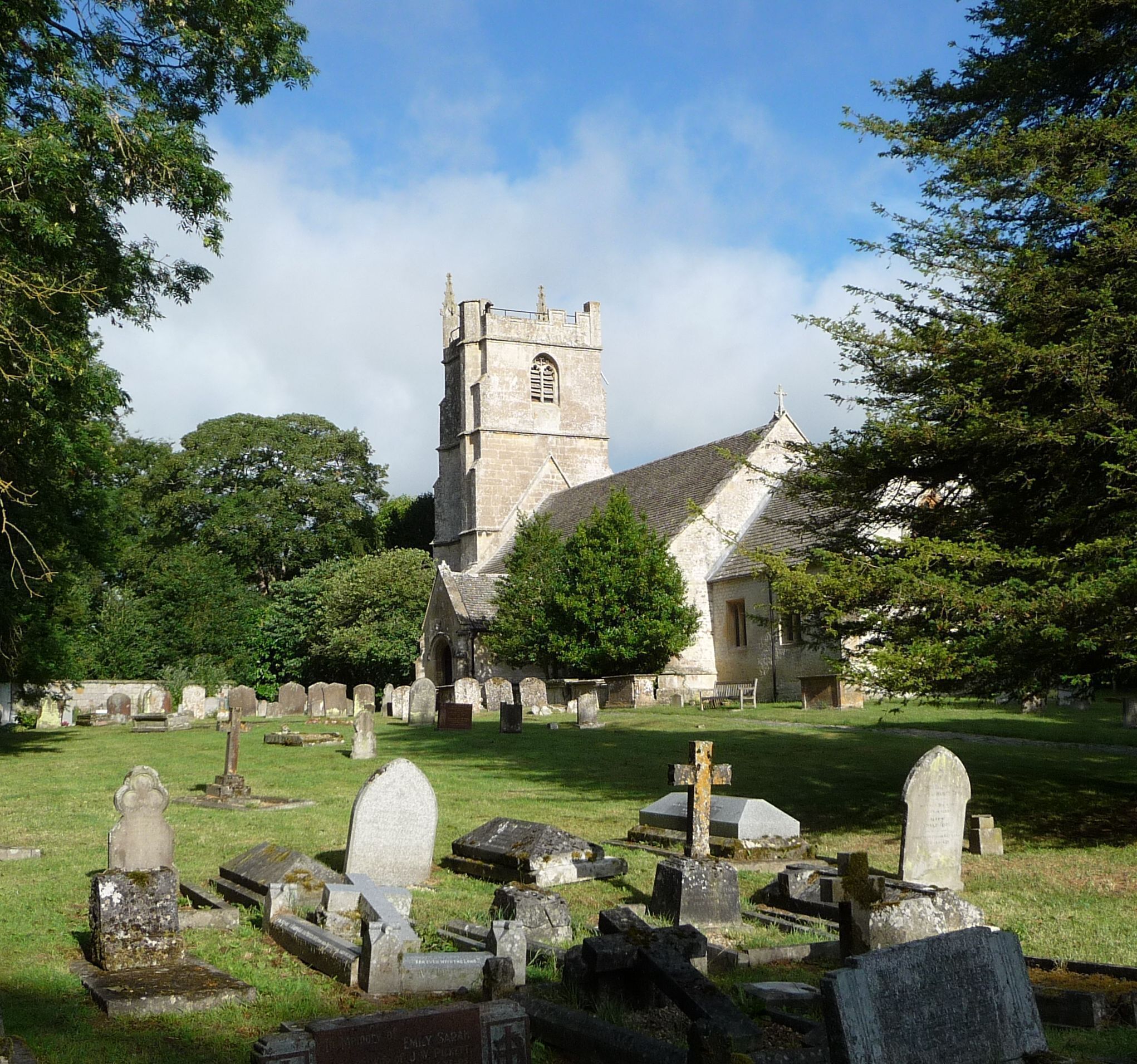 A church with a tall tower and a graveyard in front.