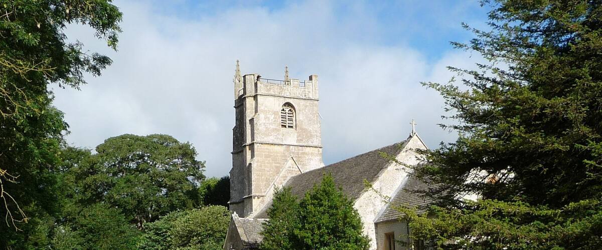 A church with a tall tower and a graveyard in front.