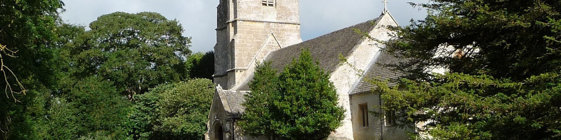 A church with a tall tower and a graveyard in front.