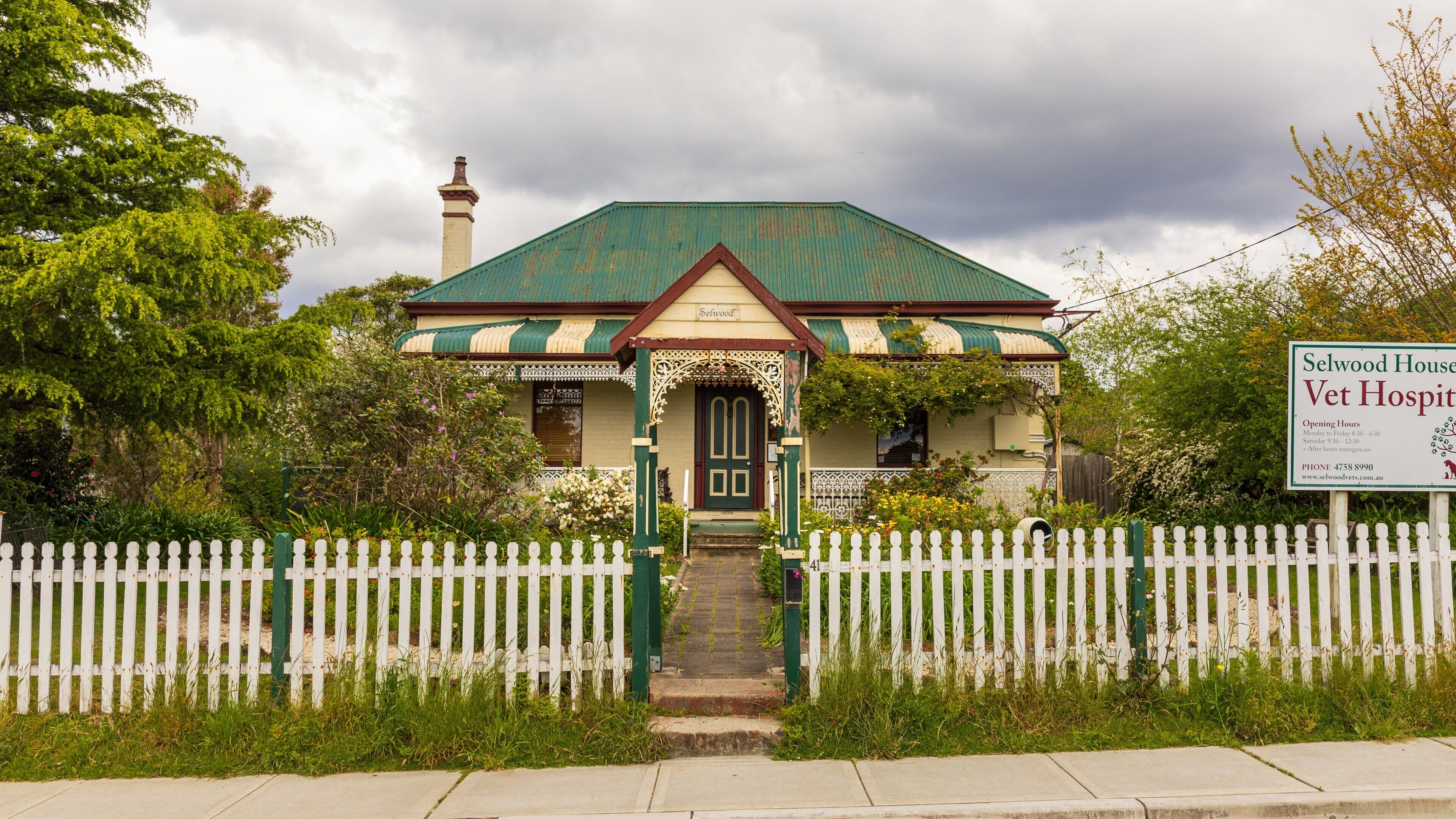 A traditional house with a green roof and white picket fence.