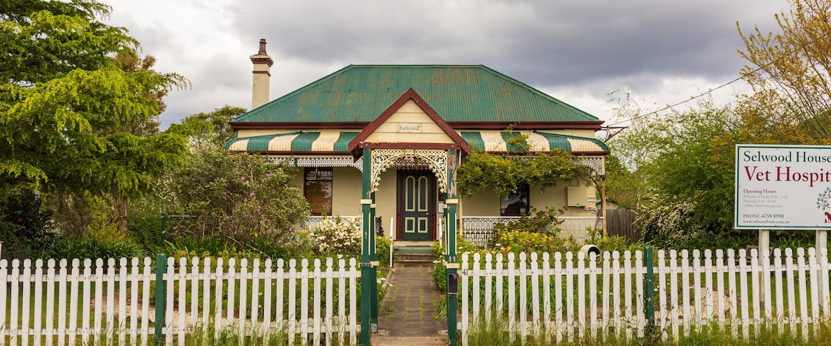 A traditional house with a green roof and white picket fence.