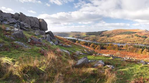 A mountainous landscape with a lake, autumn foliage, and rocky terrain.
