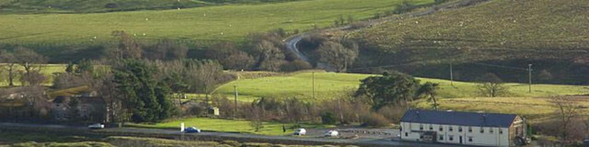 Rolling green hills, a white building, and a winding road.