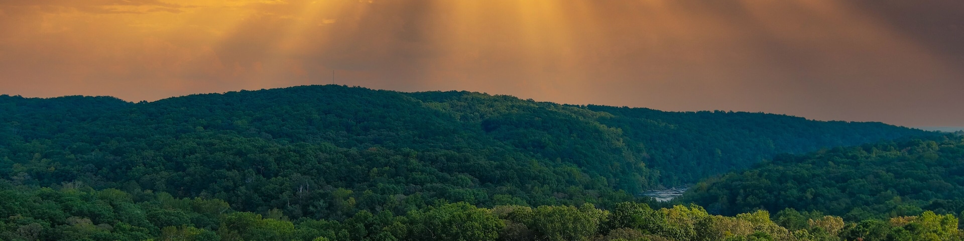 a majestic aerial shot of vast miles of lush green trees with the Chattahoochee river running through them with powerful clouds at Sweetwater Creek State Park in Lithia Springs Georgia
