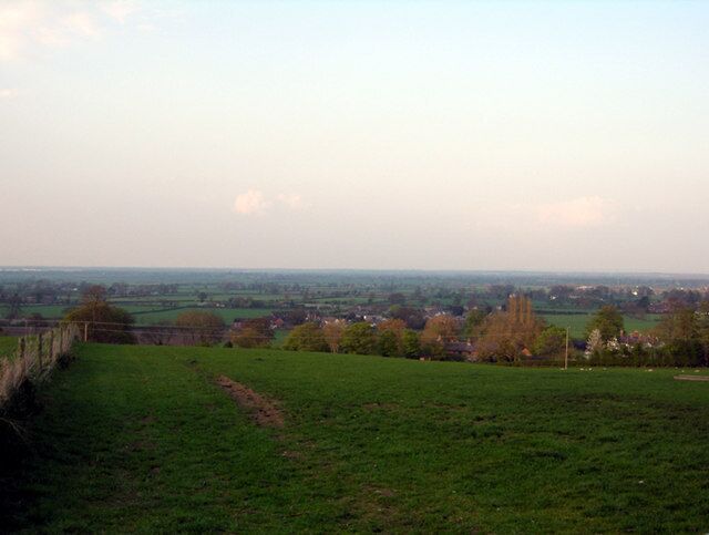 Cheshire Plain Looking down the fields from Higher Lane towards the North with the roofs of the Burton Hamlet and the Cheshire Plain in the background.