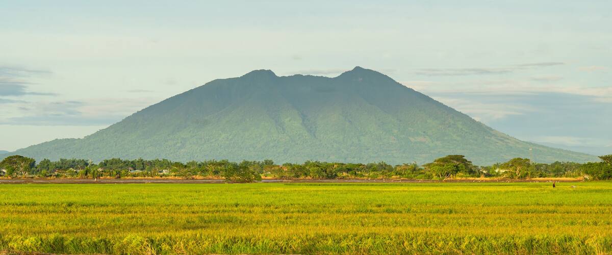 A mountain range with a foreground of green fields.