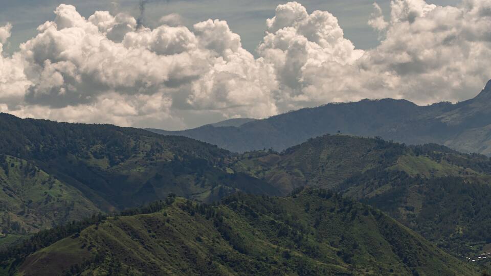 A mountainous landscape with rolling hills and a cloudy sky.
