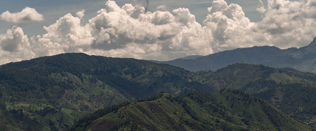 A mountainous landscape with rolling hills and a cloudy sky.