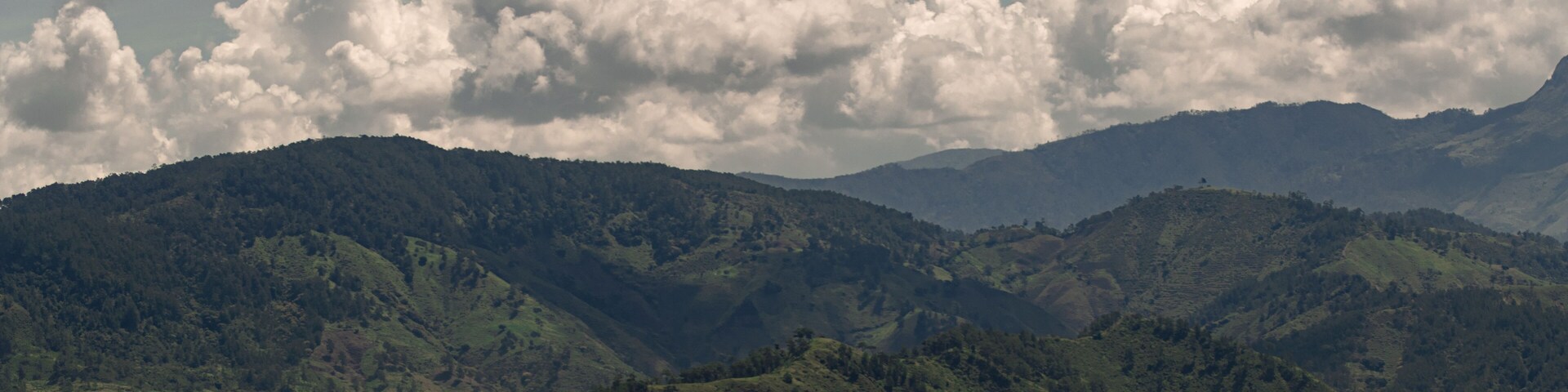 A mountainous landscape with rolling hills and a cloudy sky.