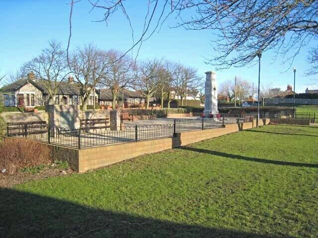 A park with a fountain, benches, and a white tower.