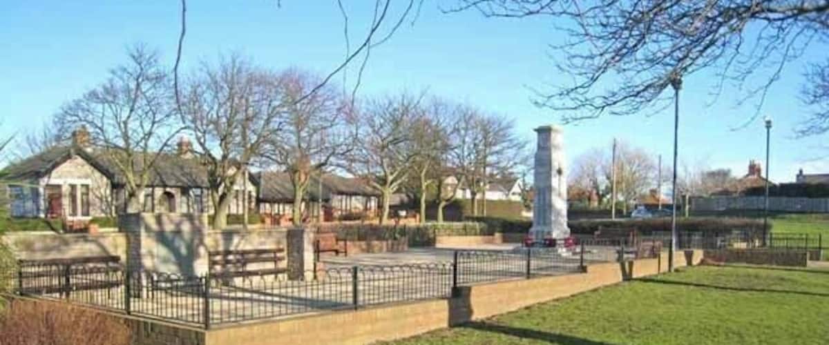 A park with a fountain, benches, and a white tower.