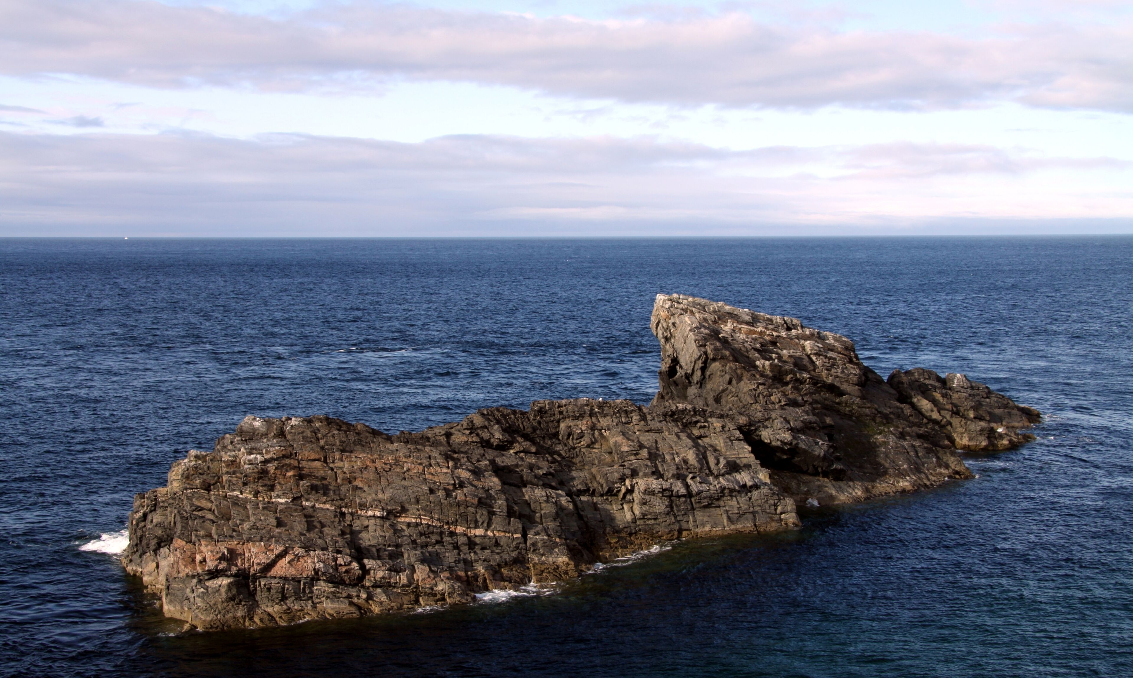 A rocky coastline with a prominent rock formation extending into the sea.