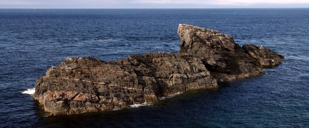 A rocky coastline with a prominent rock formation extending into the sea.