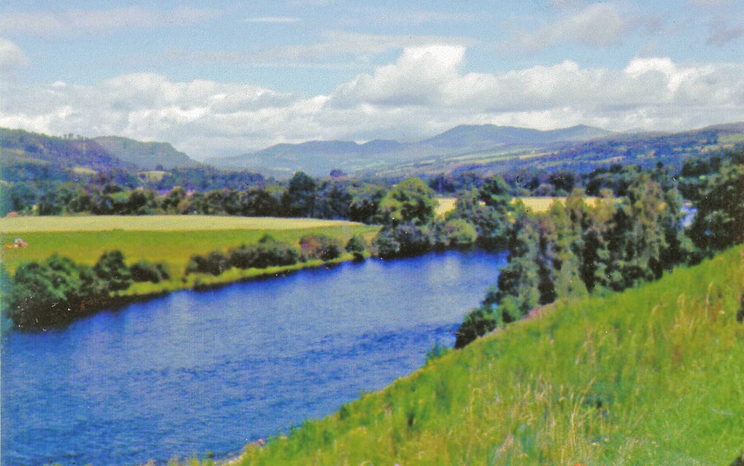 A river winding through a green landscape with hills in the background.