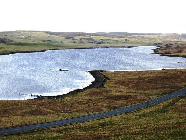 Nousta Skerry, Effirth Voe, Shetland. The community of Effirth is in the distance across the voe.