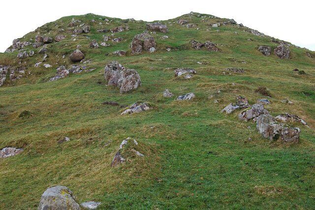 Dun Eyre There is not a lot of the structure of the dun left to be seen, though there is no doubting the remains. It sat on top of this eminence, about 150m above Loch Eyre. The eminence itself is about 5m above the surrounding land. This view is looking up to the site with a double row of boulders marking the approach to the fort.