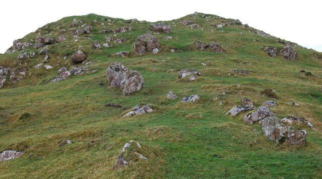 Dun Eyre There is not a lot of the structure of the dun left to be seen, though there is no doubting the remains. It sat on top of this eminence, about 150m above Loch Eyre. The eminence itself is about 5m above the surrounding land. This view is looking up to the site with a double row of boulders marking the approach to the fort.