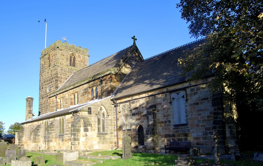 A historic stone church with a bell tower and a graveyard.