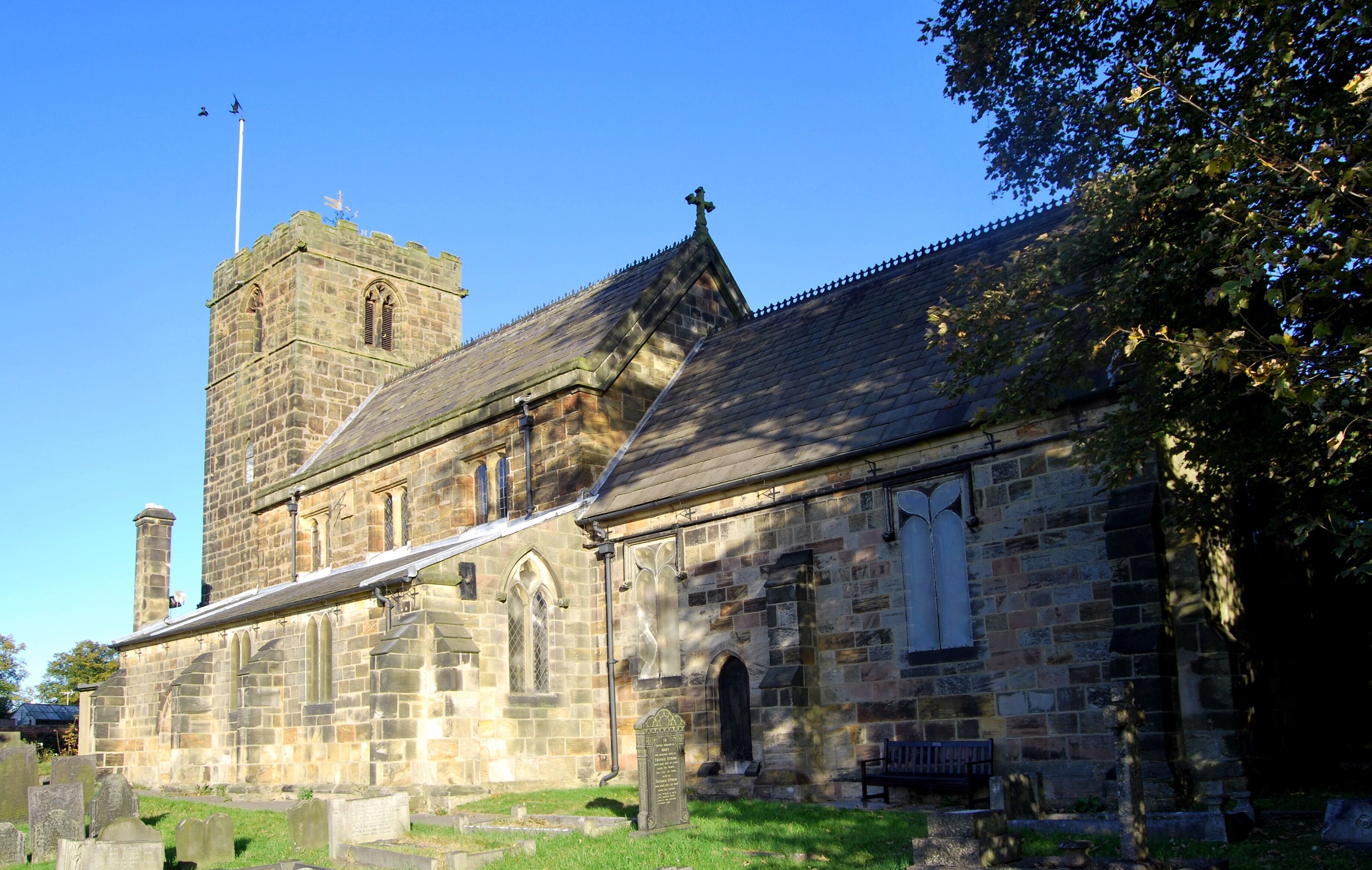 A historic stone church with a bell tower and a graveyard.