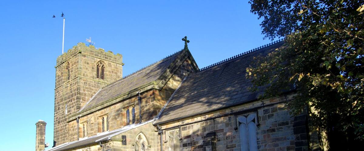 A historic stone church with a bell tower and a graveyard.