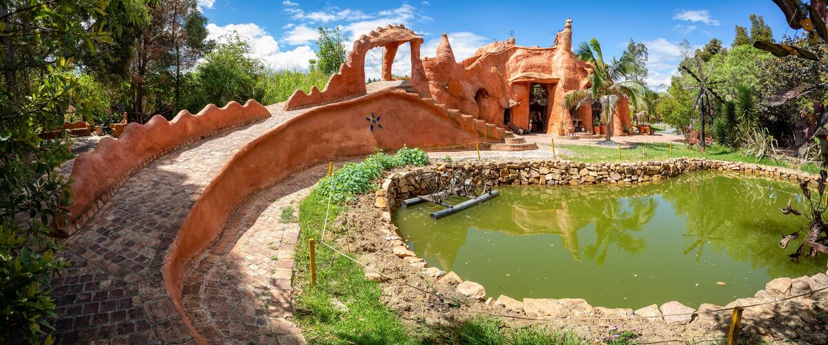 A terraced garden with a pond, stone walls, and a building with a unique architectural style.