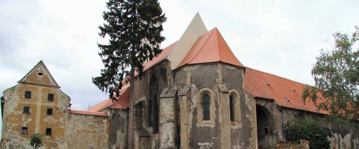 An old church with a red roof and a large tree in front.