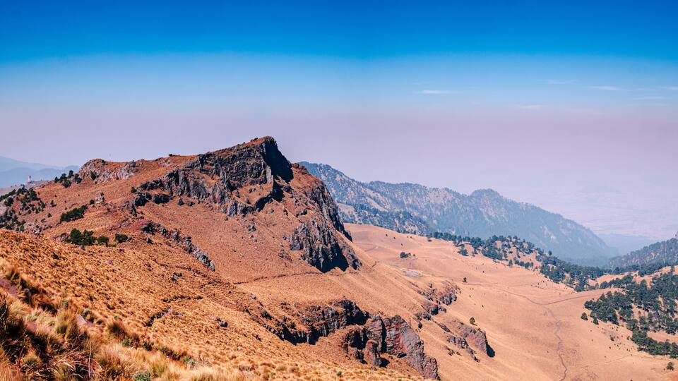 A rugged mountain landscape with rocky peaks and sparse vegetation.