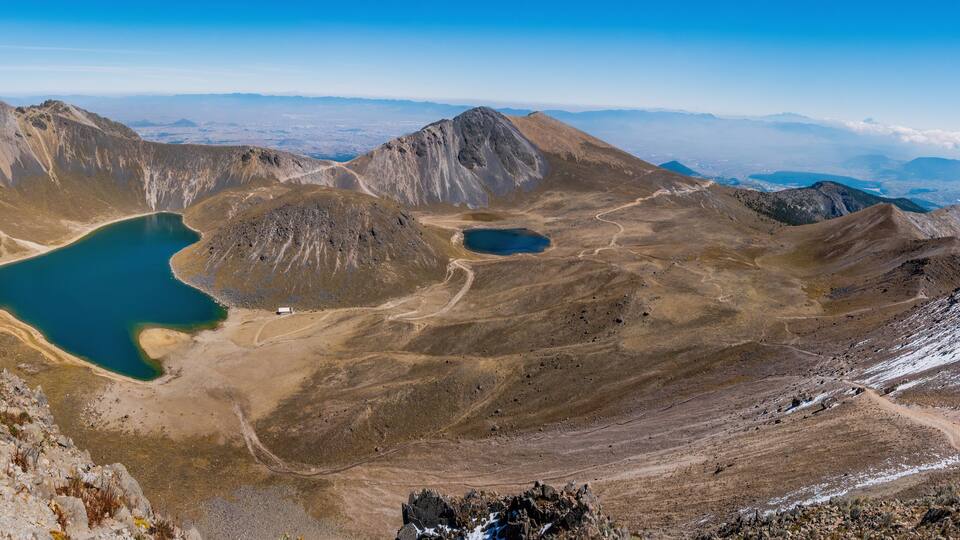 A mountainous landscape with two lakes and a winding road.