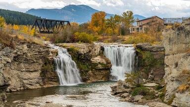 Lundbreck Falls, a waterfall of the Crowsnest River in autumn foliage season. An iron bridge for railroad tracks in the background. Alberta, Canada.