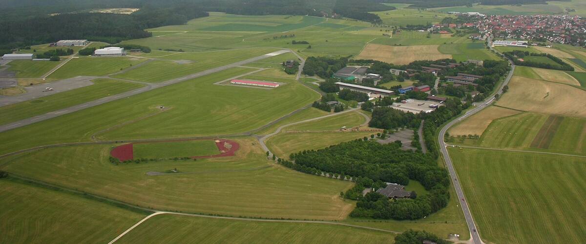 An aerial view of a rural landscape with fields, a small village, and a few buildings.