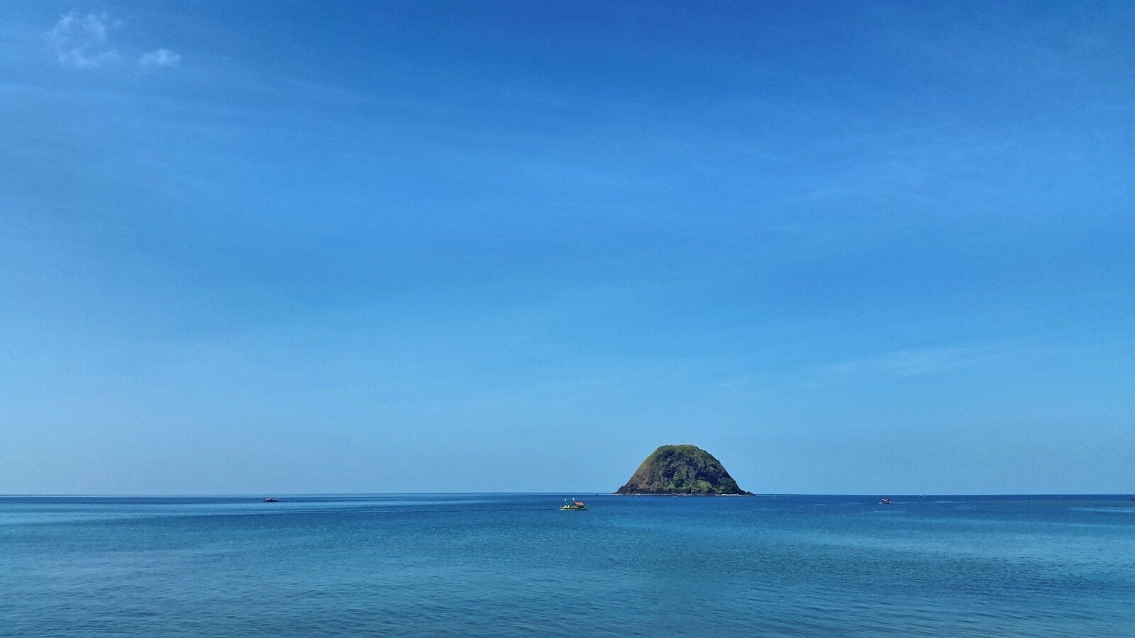 A clear blue sea with a small island in the distance.